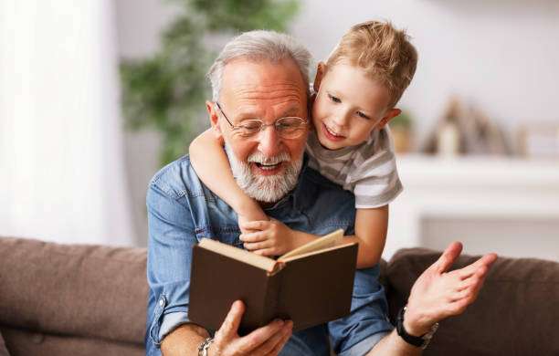 1687846989 cheerful grandfather and grandson reading book together